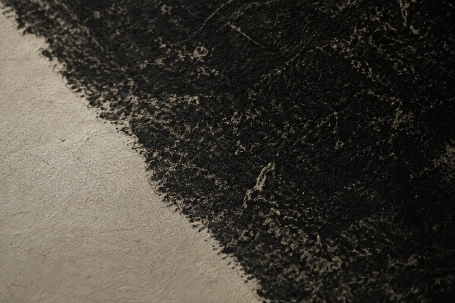 Detail of an ink stone-rubbing texture on handmade paper.