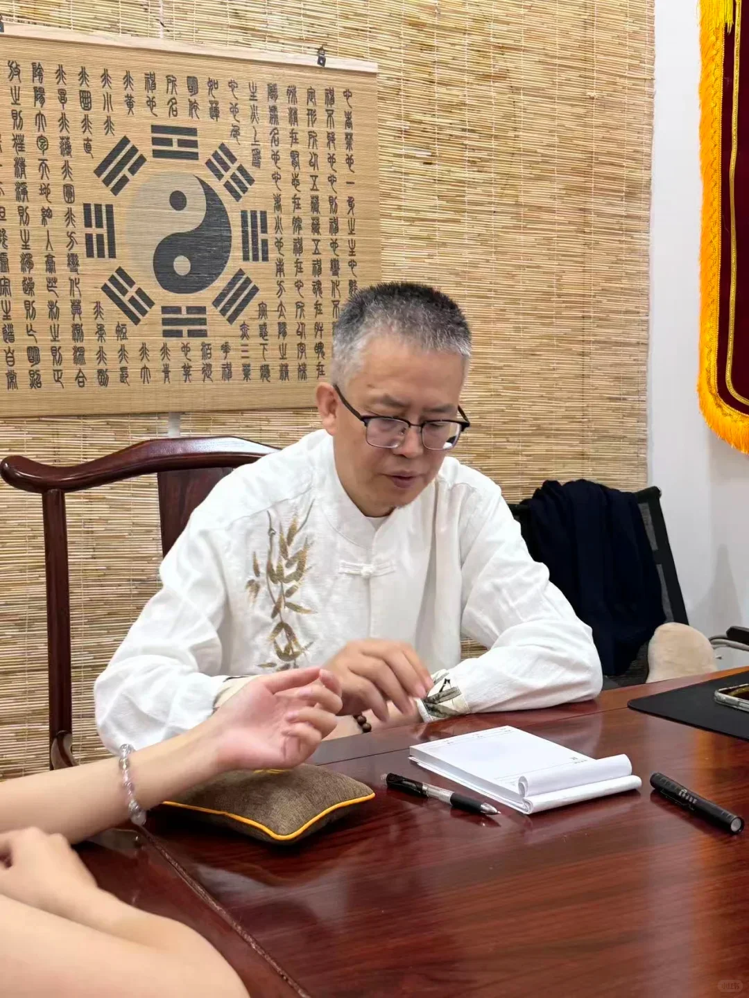 An in-person pulse consultation at a wooden desk
