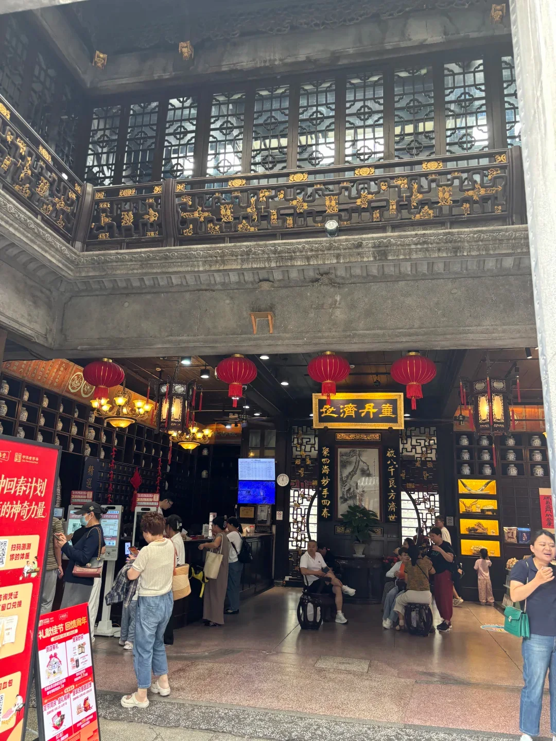 Visitors beneath red lanterns inside a traditional Chinese pharmacy