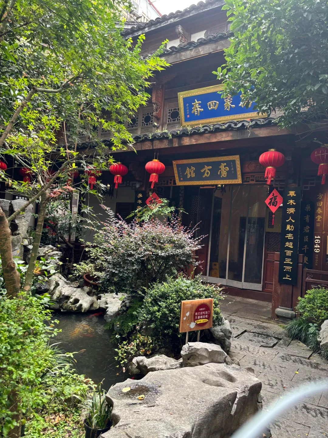 A leafy courtyard with stone paths and traditional wooden buildings