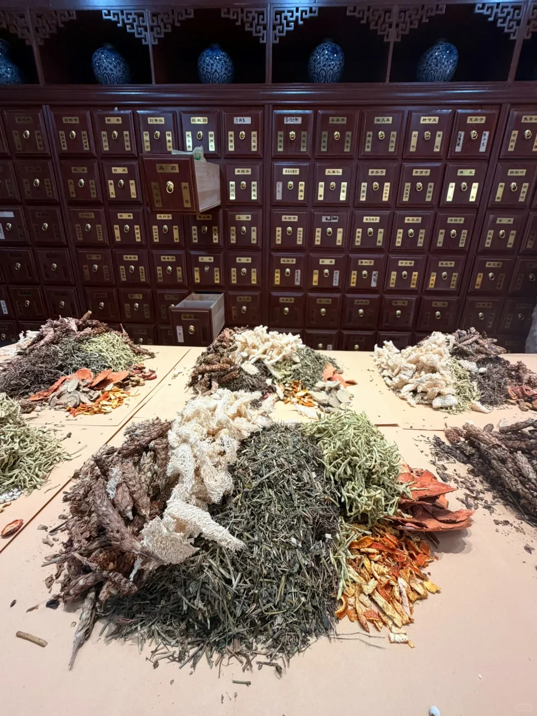 Dried botanical materials arranged in front of medicine drawers