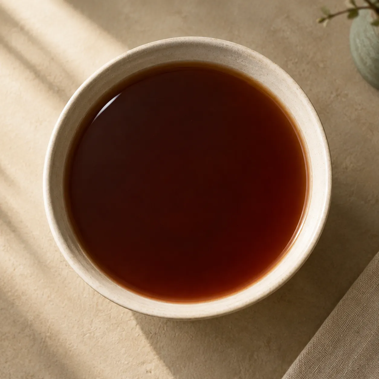 A dark red-brown decoction in a plain white bowl, seen from above.
