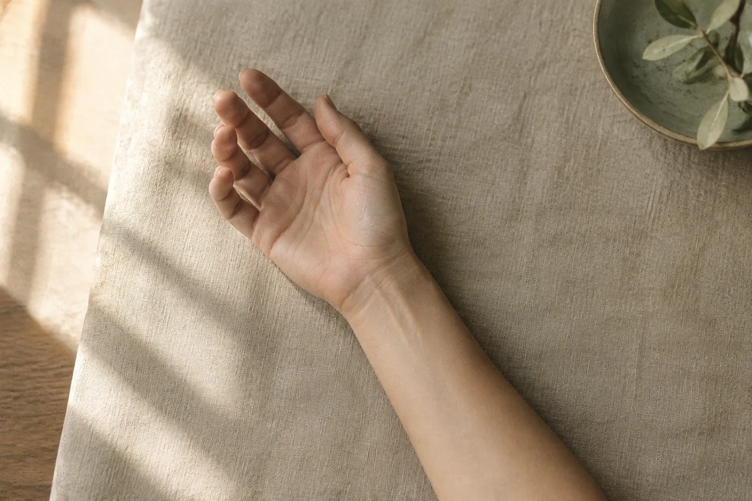 A wrist resting palm-up on linen.